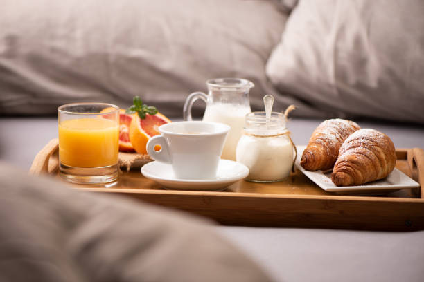 istock Continental breakfast. Breakfast tray on bed with coffee, orange juice and croissant 1202557113
