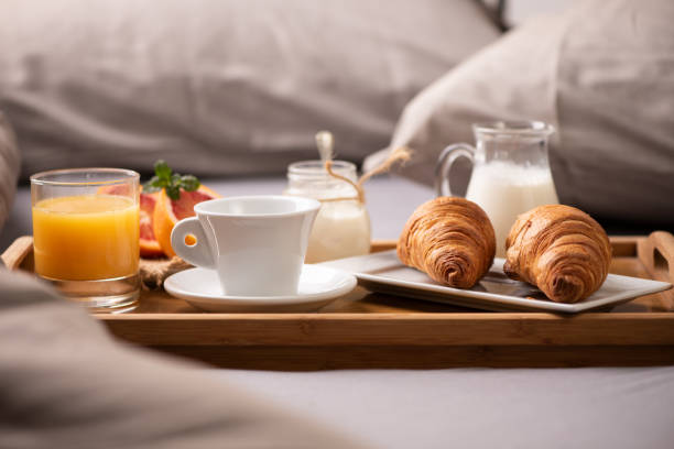 istock Continental breakfast. Breakfast tray on bed with coffee, orange juice and croissant 1202557164