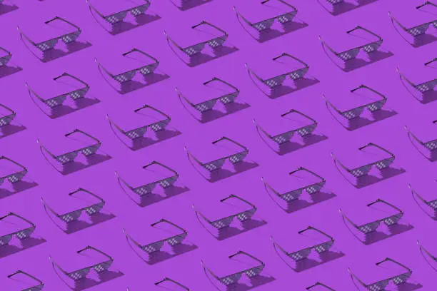 Creative pattern from protective pixel glasses using for work with computer screens, phones and TV on a purple background with hard shadows.