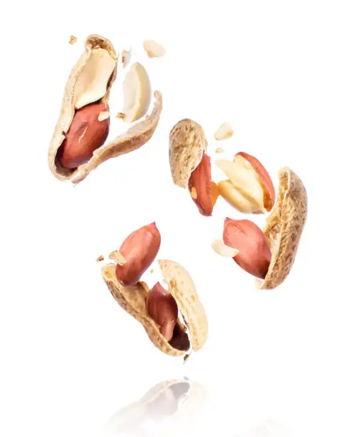 Group of crushed peanuts in the air close-up on a white background