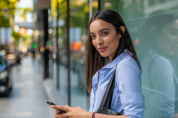istock Young hispanic woman using a phone and looking at the camera 1202559401