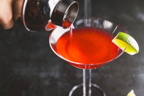 istock Pouring red cocktail with lime in Martini glass on a table. 1202561341