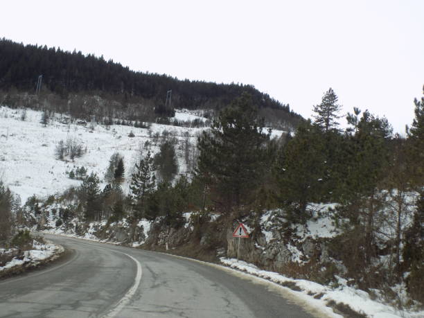istock Driving the winding road through the woods during the winter 1202561479
