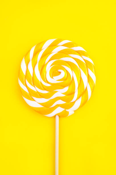 pirulito amarelo na forma de um círculo em um fundo amarelo. - flavored ice lollipop candy affectionate - fotografias e filmes do acervo