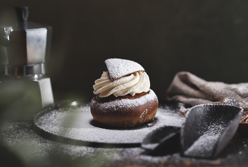 A traditional baked dessert from Sweden knows as a semla on a wooden table. This version here is a Vörtsemla made on brown bread with whipped cream.