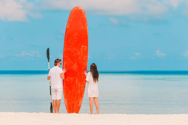 istock Young couple with red surfboard during tropical vacation 1202562741
