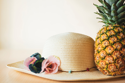 Straw hat and pineapple symbolizing traveling to warm tropical countries. Color image.