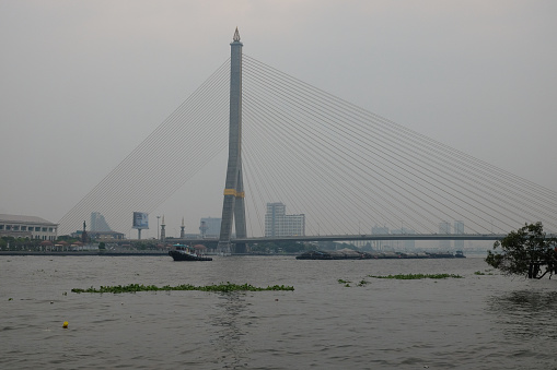 Bangkok, Thailand, December 28, 2018. River transport floats near the bridge over the Chao Phraya River in the capital of Thailand.