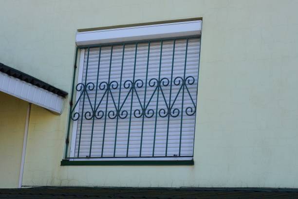 istock one square window with white shutters behind a green iron grate with a forged pattern 1202564386