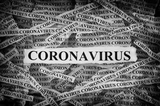 Strips of newspaper with the word Coronavirus typed on them. Black and White. Close up.