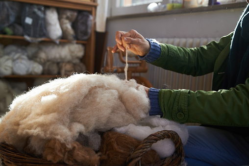 handmade manufacturing yarns from natural sheep wool, female hands closeup