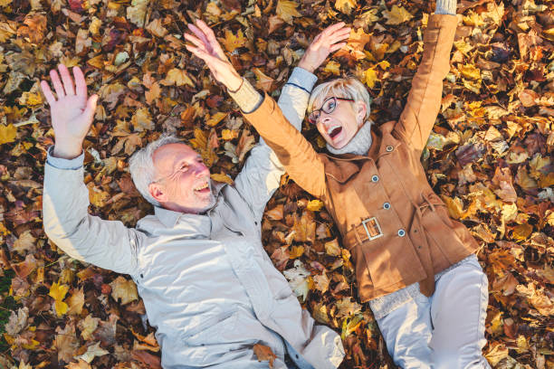 istock Cheerful active senior couple lying on ground rolling around in autumn leaves having fun 1202566739