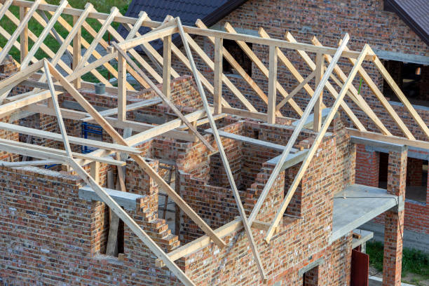 istock Unfinished brick house with wooden roof structure under construction. 1202566901