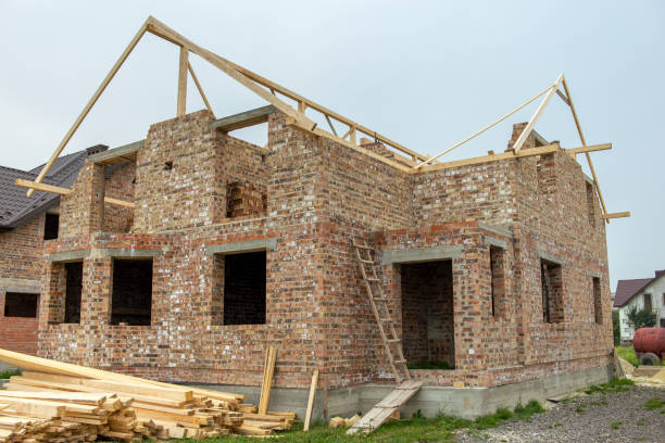 istock Unfinished brick house with wooden roof structure under construction. 1202567011