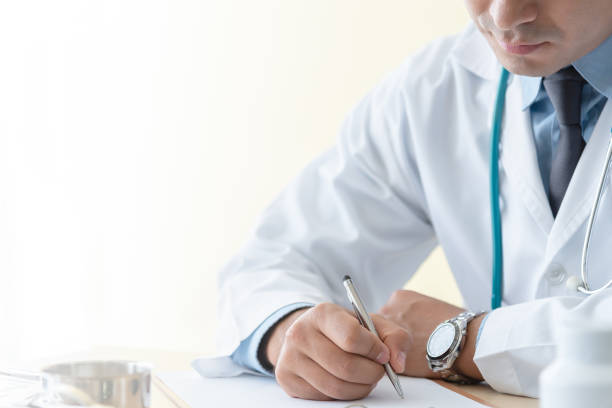 istock Doctor writing prescription selective focus. Young man physician with stethoscope prescribing treatment to patient. Doctor with pen writing recipe on clipboard in hospital. 1202567866