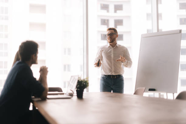 istock Young casual businessman presenting new project to partners 1202568958