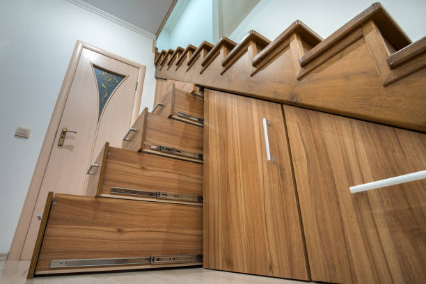 istock Modern architecture interior with luxury hallway with glossy wooden stairs in multi-storey house. Custom built pullout cabinets on glides in slots under stairs. Use of space for storage. 1202569792