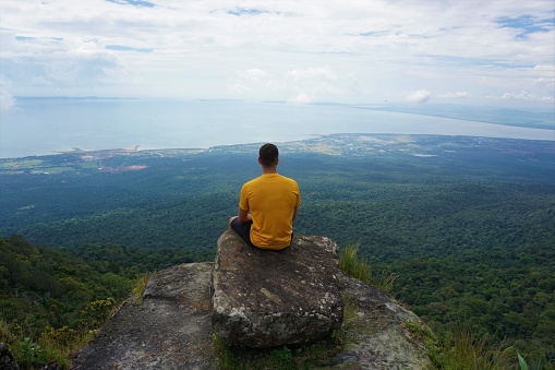 Man sitting on top of a mountain and enjoys the amazing view