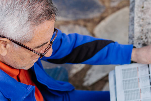 istock Senior man with glasses reading newspaper at park, top view 1202574717