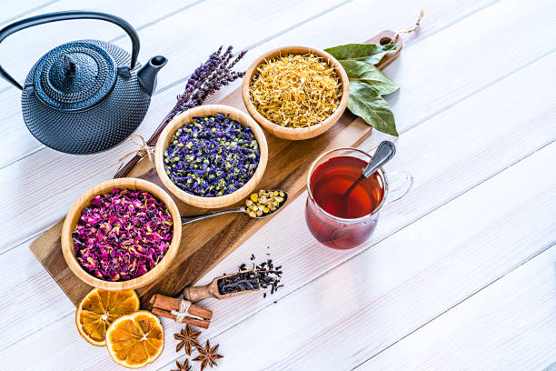 istock Herbal tea cup with various multi colored dried tea leaves and flowers shot on white table 1202577116