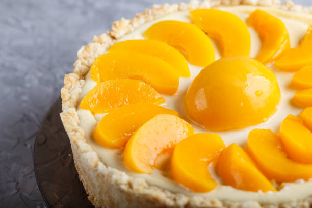 istock Round peach cheesecake on a gray concrete background. side view, close up. 1202577718