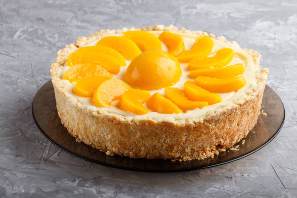 istock Round peach cheesecake on a gray concrete background. side view, close up. 1202578317
