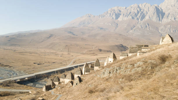 Road among the mountains and construction of tombs of the city of the dead Dargavs in North Ossetia-Alania in Russia stock photo