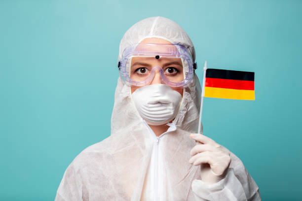 medic woman wearing protective clothing against the virus holds Germany flag stock photo