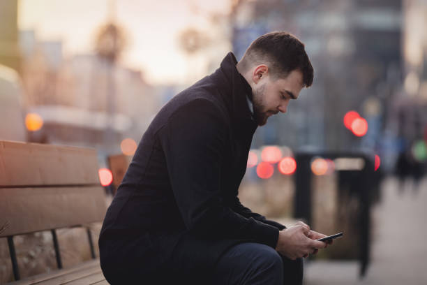 istock young man with a mobile phone is sitting on a bench 1202585096
