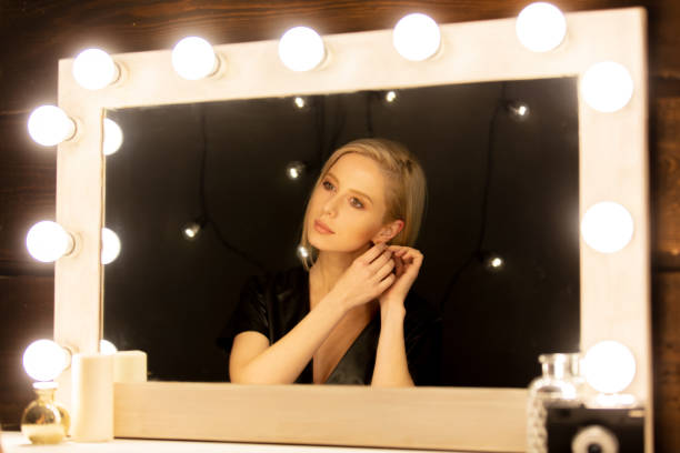 Beautiful blonde woman near makeup mirror Beautiful blonde woman near makeup mirror backstage mirror stock pictures, royalty-free photos & images