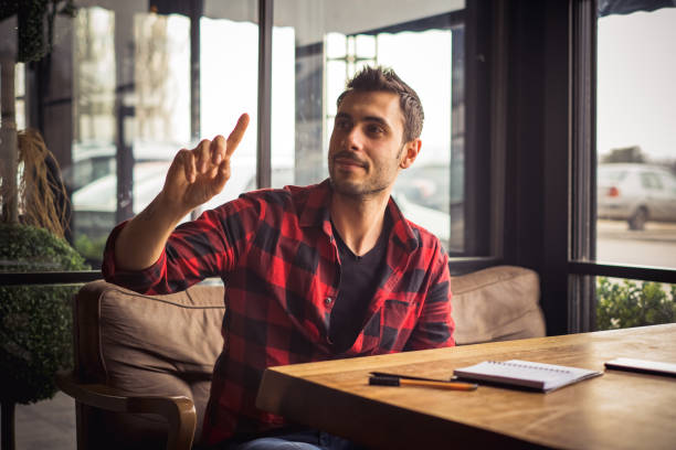 istock Young man calling a waiter in coffee shop 1202588389