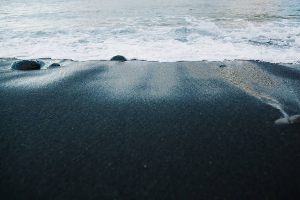 istock Foamy Sea Water Coming on Black Sand Copyspace 1202588660