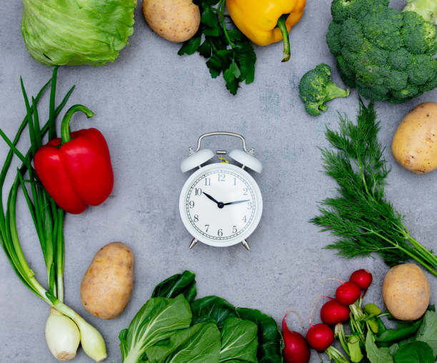istock Alarm clock and vagetables on table. 1202589706