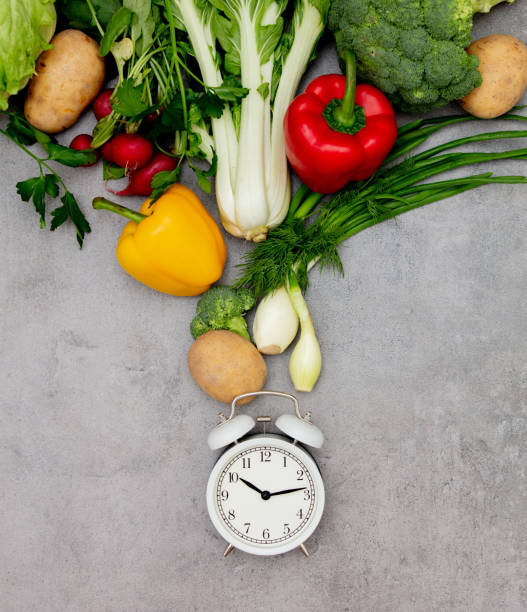 istock Alarm clock and vagetables on table. 1202589819