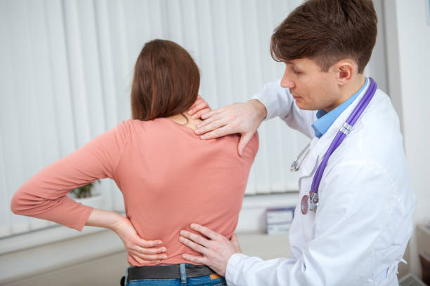 jeune femme sur un rendez-vous médical avec son docteur - doctor patient chiropractic adjustment communication photos et images de collection