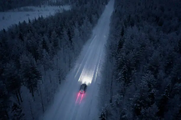 Photo of Aerial view of a snow road going through in the snow covered forest in Finland