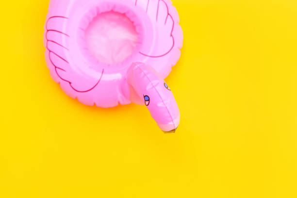 istock Summer beach composition. Simply minimal design with pink Inflatable flamingo isolated on yellow background. Pool float party, trendy celebrity fashion concept. Flat lay top view copy space 1202605410