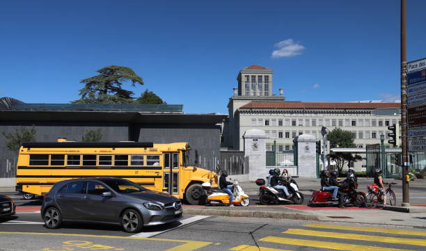 An American-style school bus and European traffic at an intersection in front of the World Trade Organization building in Geneva, Switzerland