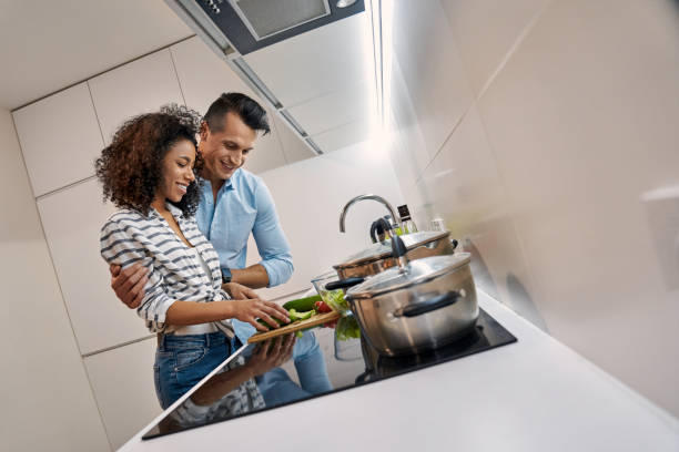 Romantic Date. Young multiethnic couple standing at kitchen cooking dinner cutting vegetables for salad cheerful