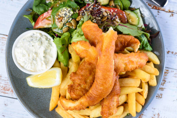 talerz "fish and chips" z poobijanymi rybami, chipsami ziemniaczanymi, sałatką, sosem tatarskim i klinem cytrynowym. - fish and chips cafe restaurant salad zdjęcia i obrazy z banku zdjęć