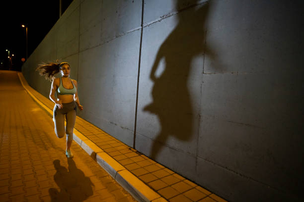 shadow is after her - night running imagens e fotografias de stock