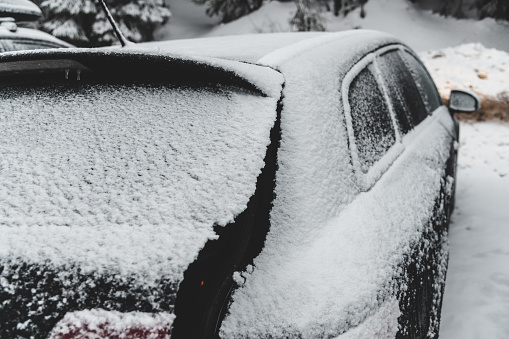Black car covered in snow, ice on the windows