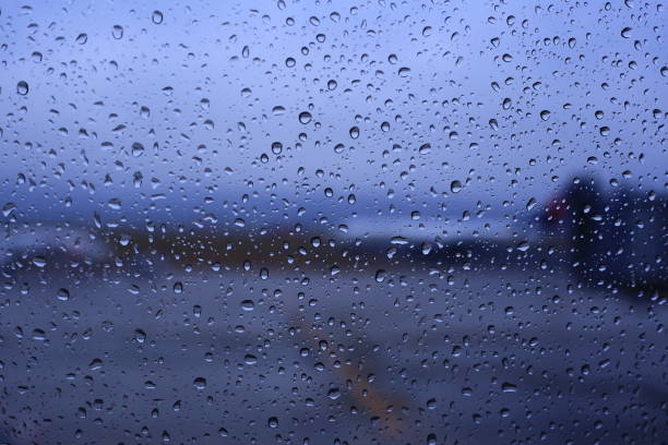 공항에서 악천후. 공항 터미널 창에 빗방울이 적발되어 승객이 탑승을 기다리는 동안 비행기 선착장과 화물을 적재하는 초점 사진이 흐려집니다. - runway airport rain wet 뉴스 사진 이미지