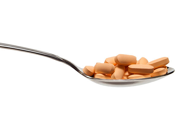 Spoonful of Pills Close-up of a spoon full of prescription pills. statin stock pictures, royalty-free photos & images