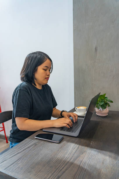 istock Asian woman freelancing on laptop at rustic coffee table 1202649088