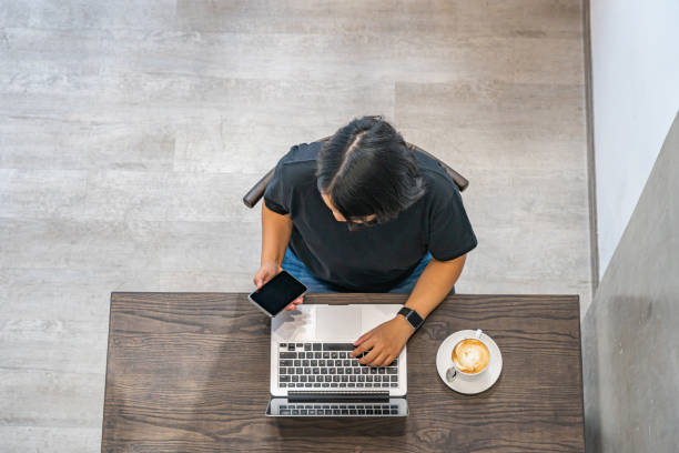 istock Woman using smartphone and laptop at minimalism coffee shop 1202649421