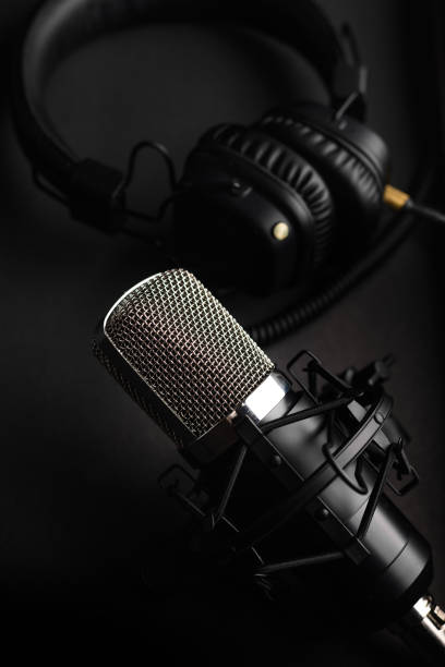 istock Studio microphone with professional headphones. Black on a black background 1202650135