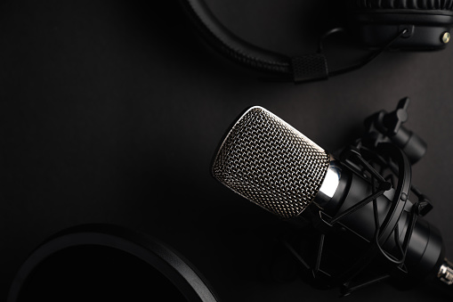 Black studio microphone on a black background with a pop filter with space for design, baner with space