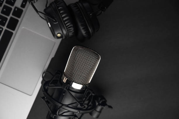 istock Studio black studio microphone with studio headphones on a laptop on a black background. Banner. Radio, work with sound, podcasts, blogging. 1202650216