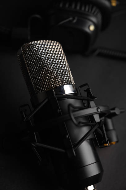 istock Microphone for podcasts and studio headphones on a black background, vertical frame 1202652012